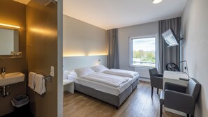 A modern hotel room with a bed, bedside table, and a desk with a chair. - mk | hotel stuttgart (Stuttgart)