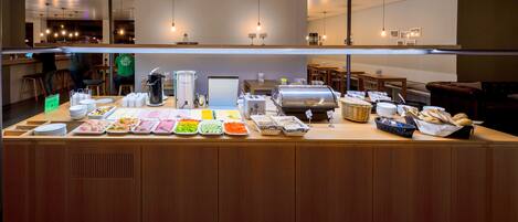 A buffet counter with various food items and a grill.