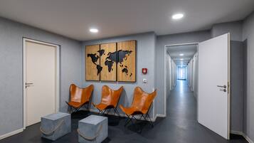 A modern waiting area with a world map artwork, leather chairs, and a long hallway.