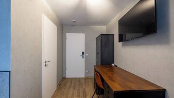 Kapea käytävä, jossa on puinen työpöytä, tuoli ja vaatekaappi.