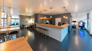 A modern bar area with a wooden counter, bar stools, and pendant lighting. - mk | hotel stuttgart (Stuttgart)