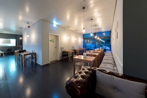Un restaurant moderne doté d’un long comptoir, de sièges en cuir et d’un éclairage suspendu.
