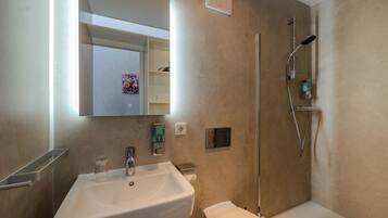 A modern bathroom with a sink, toilet, and shower.