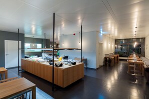 A modern kitchen area with a central island, wooden tables, and a seating area with chairs. - mk | bed & breakfast stuttgart (Stuttgart)