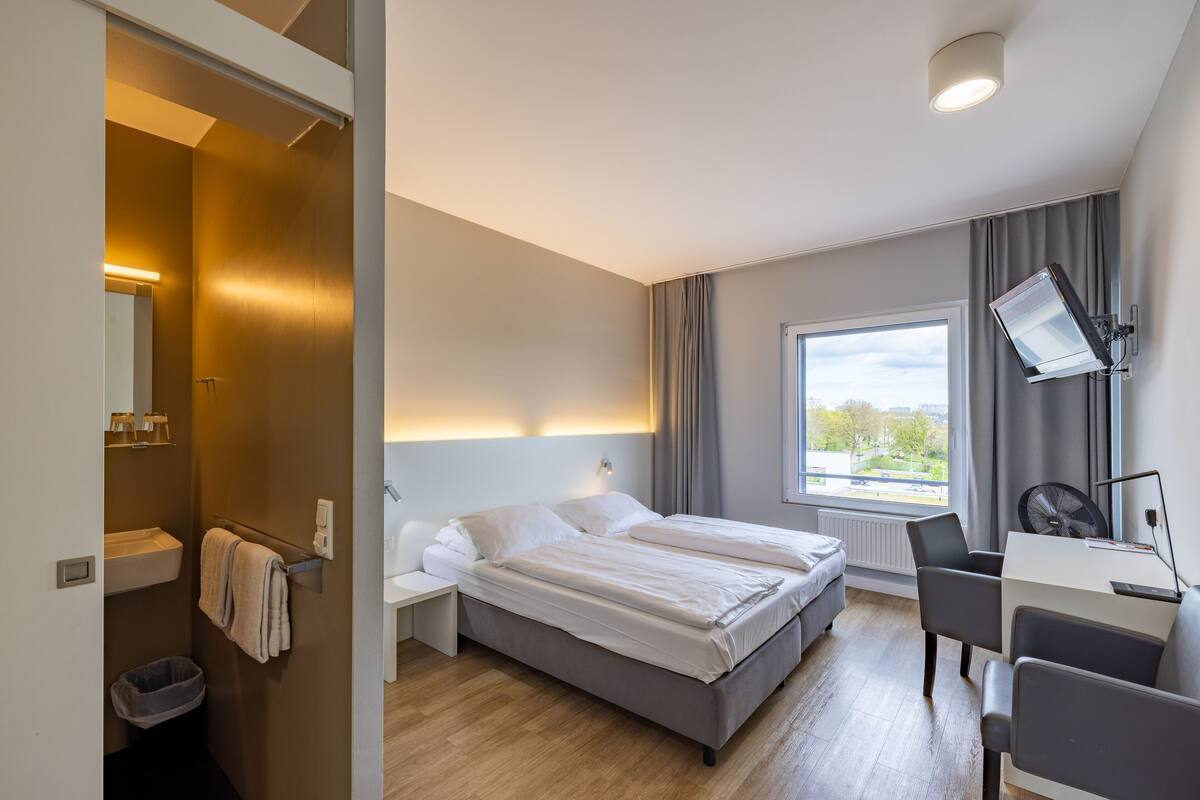 Et moderne hotelværelse med en stor seng, et skrivebord og et vindue med udsigt.