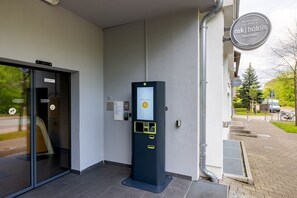 A hotel entrance with a self-service kiosk, a glass door entrance, and a sign indicating late check-in availability. - mk | hotel stuttgart (Stuttgart)