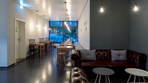 A modern interior with a long dining area, leather seating, and pendant lighting. - mk | hotel stuttgart (Stuttgart)