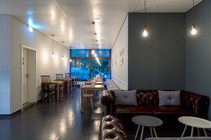 Un interior moderno con una larga zona de comedor, asientos de cuero e iluminación colgante.