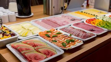 A buffet with various food options including fruits, vegetables, and meats.