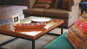Una sala de estar moderna con una mesa de centro de vidrio, un sofá y almohadones coloridos.