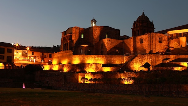 Un edificio histórico con una destacada torre campanario y una gran cúpula, rodeado por una muralla fortificada.