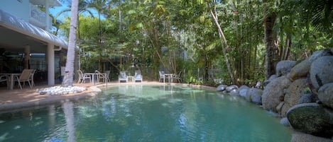 Una piscina al aire libre, sillones reclinables de piscina