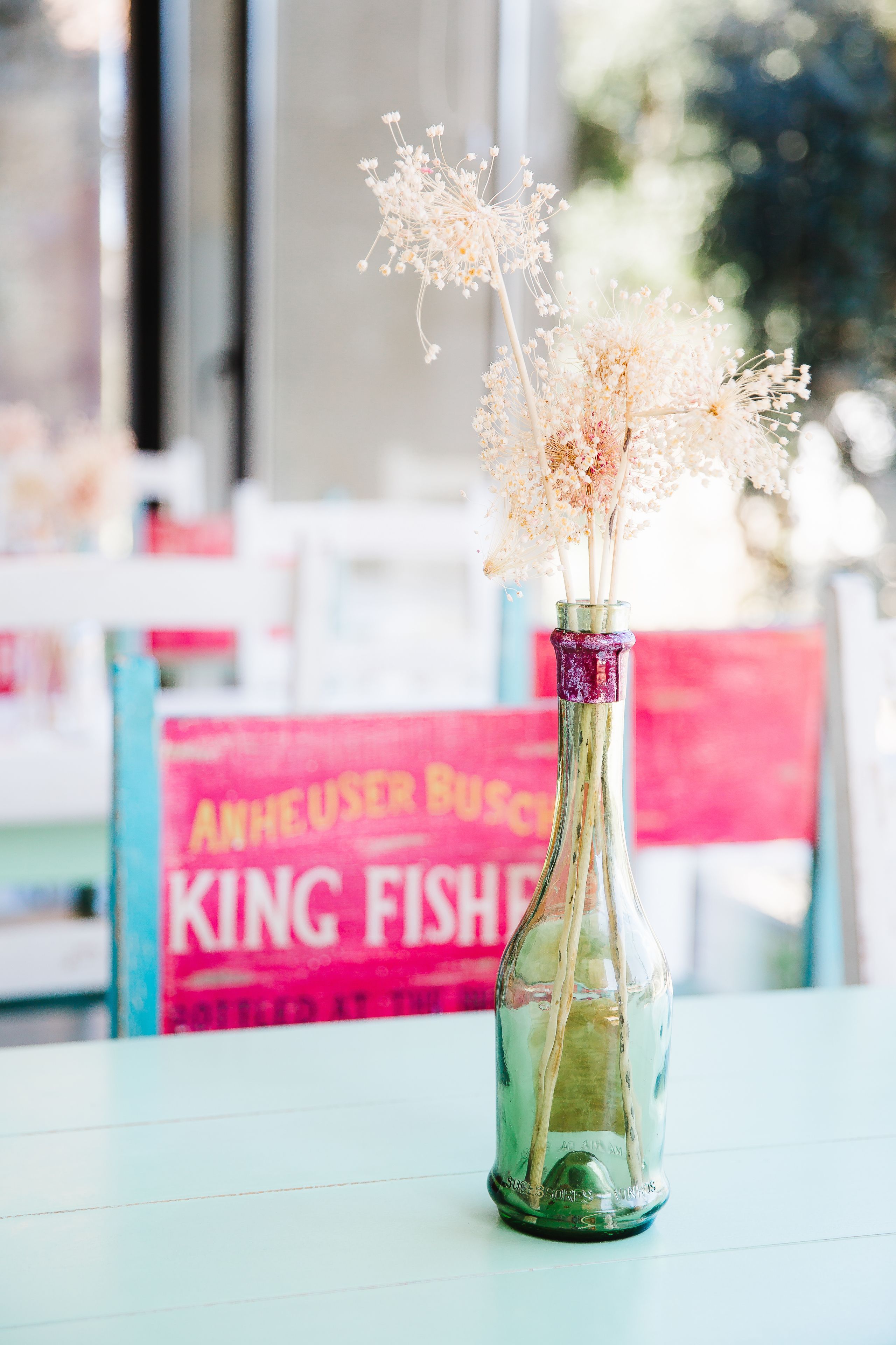 A clear glass bottle with dried flowers on a table.