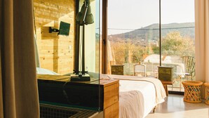 A bedroom with a large window, a bed, a desk, and a chair. - Cooking and Nature Emotional Hotel (Porto de Mos)