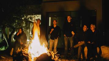 A group of people gathered around a campfire outdoors at night.