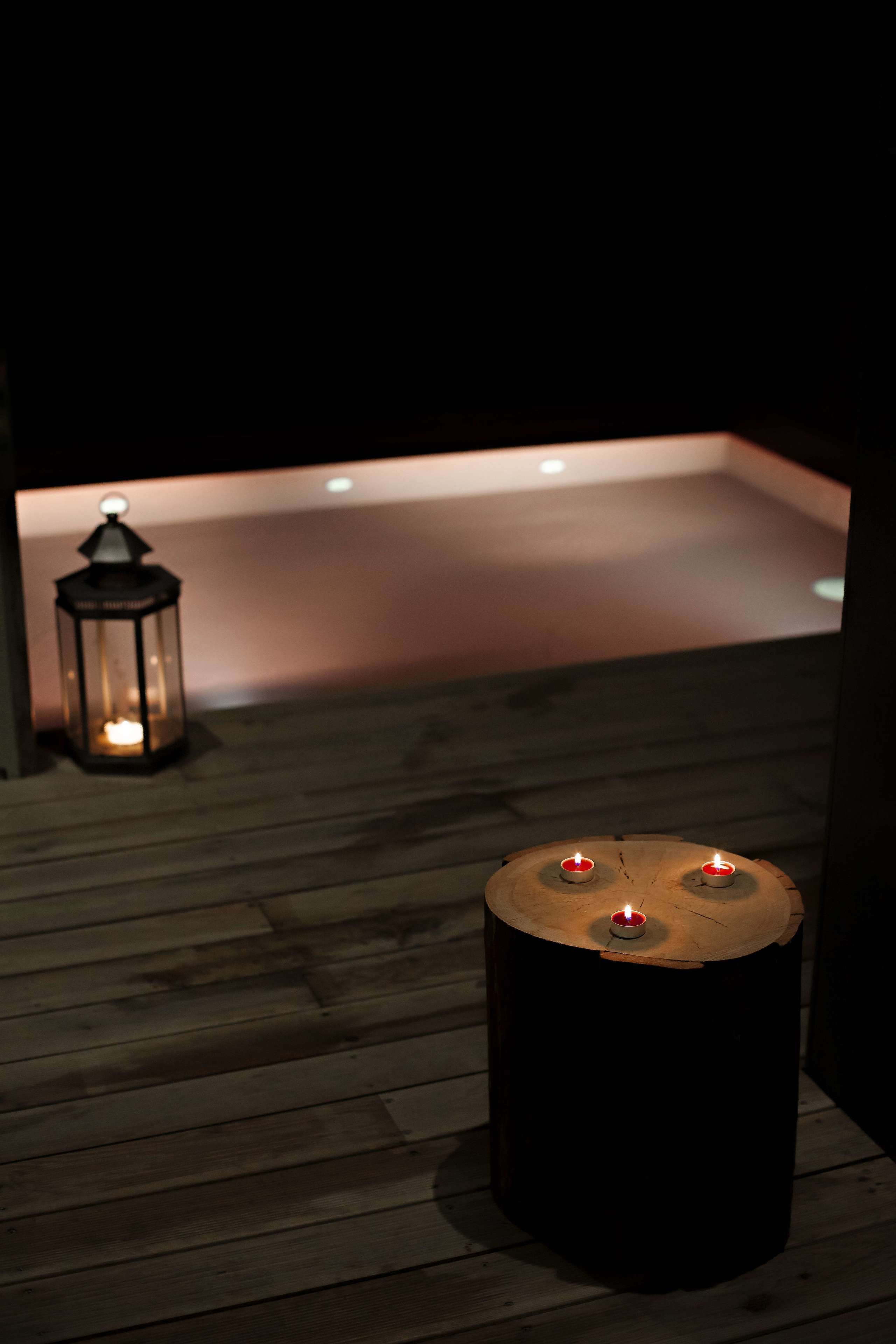 A wooden deck with a lantern and a round table with candles.
