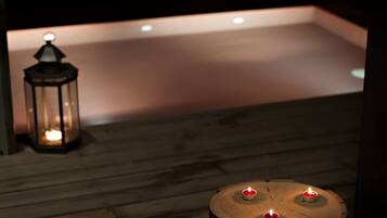 A wooden deck with a lantern and a round table with candles.