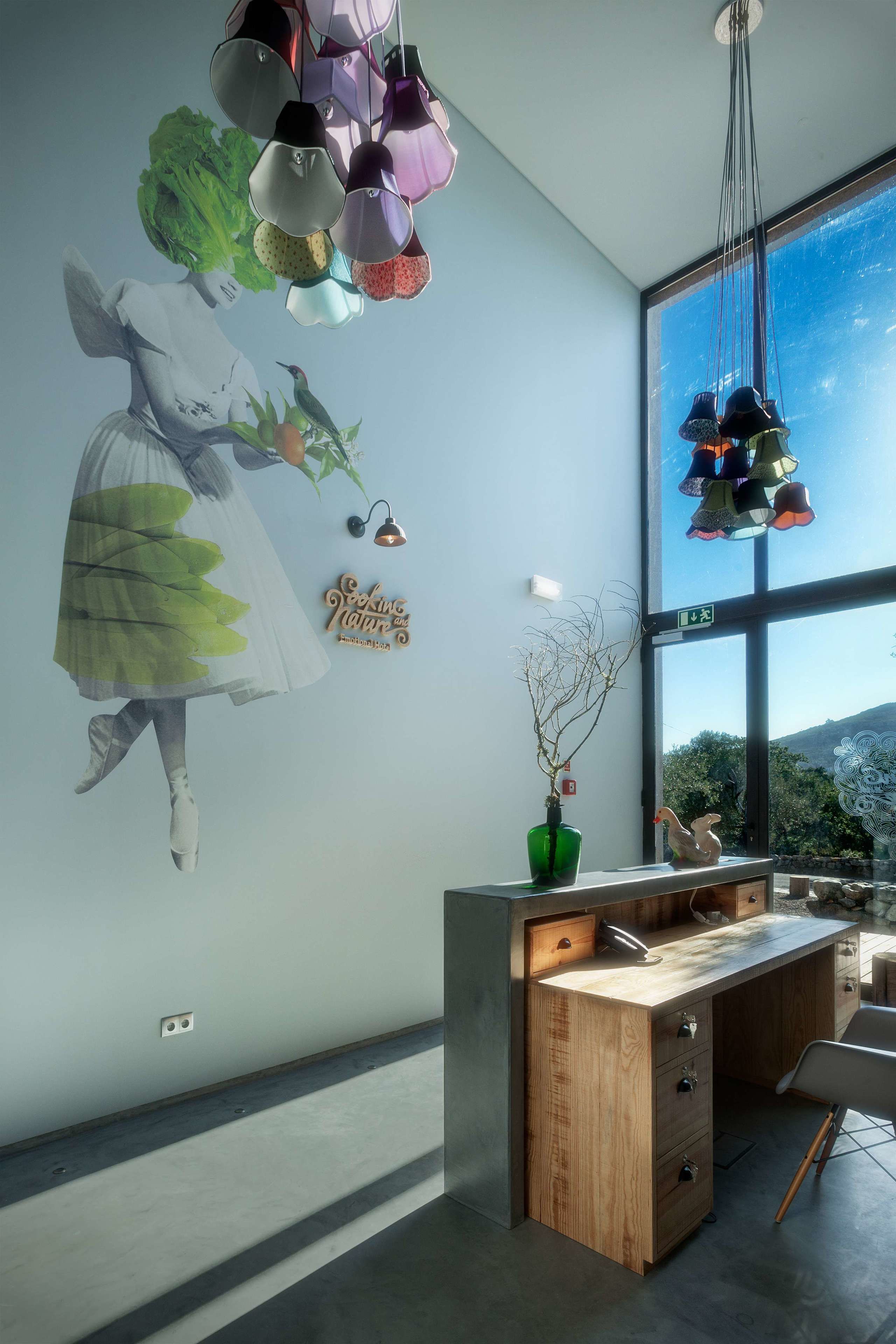 Una habitación moderna con un ventanal grande, un escritorio de madera y un mural en la pared.