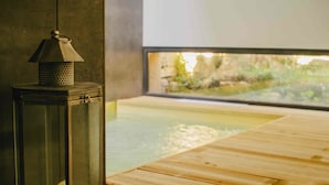 A wooden deck with a glass enclosure, a lantern, and a view of an outdoor area. - Cooking and Nature Emotional Hotel (Porto de Mos)
