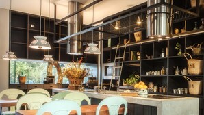 A modern kitchen with a central island, multiple hanging lights, and a view of the outdoors. - Cooking and Nature Emotional Hotel (Porto de Mos)