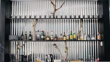 Uma área de bar com prateleiras de garrafas de bebidas, uma máquina de café e uma chaleira.