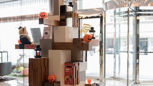 A modern lobby with a central decorative structure featuring books and pumpkins, surrounded by a pebbled floor. - Guanko Hotel (Chiayi City)