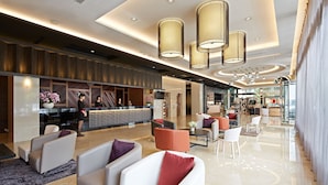 A modern hotel lobby with seating areas, a reception desk, and a view of the adjacent restaurant. - Guanko Hotel (Chiayi City)