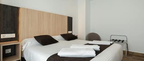 Una habitación de hotel moderna con una cama grande, una mesita de noche, una silla y un perchero para toallas.