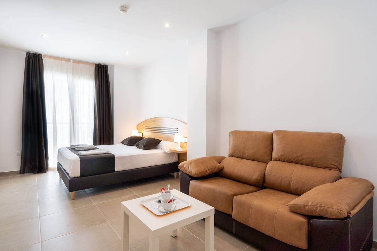Une chambre d’hôtel moderne équipée d’un lit, d’un canapé, d’une petite table et d’une table de chevet.