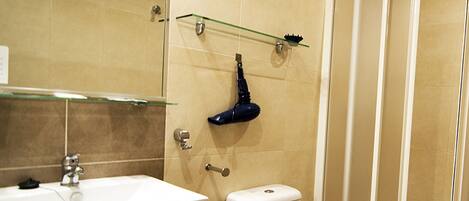 A bathroom with a white sink, a toilet, and a glass shower enclosure.