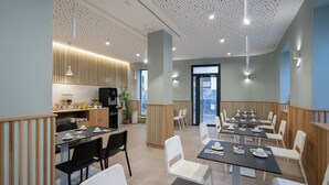 Un espace de repas moderne avec des tables et des chaises, une cuisine en arrière-plan et un plafond orné d’un motif original.