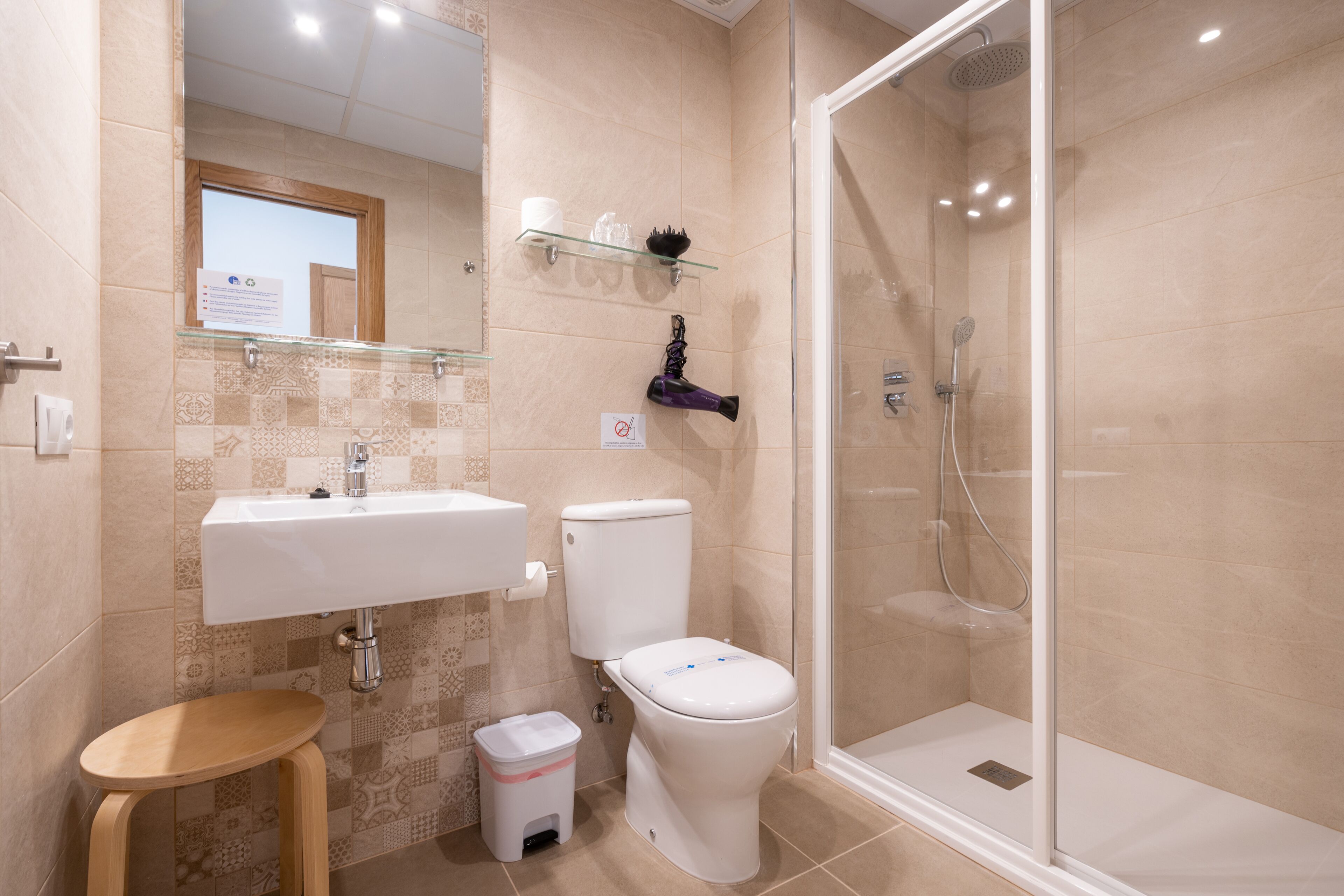 Een moderne badkamer met een douchecabine van glas, een wit wastafelmeubel en een toilet.