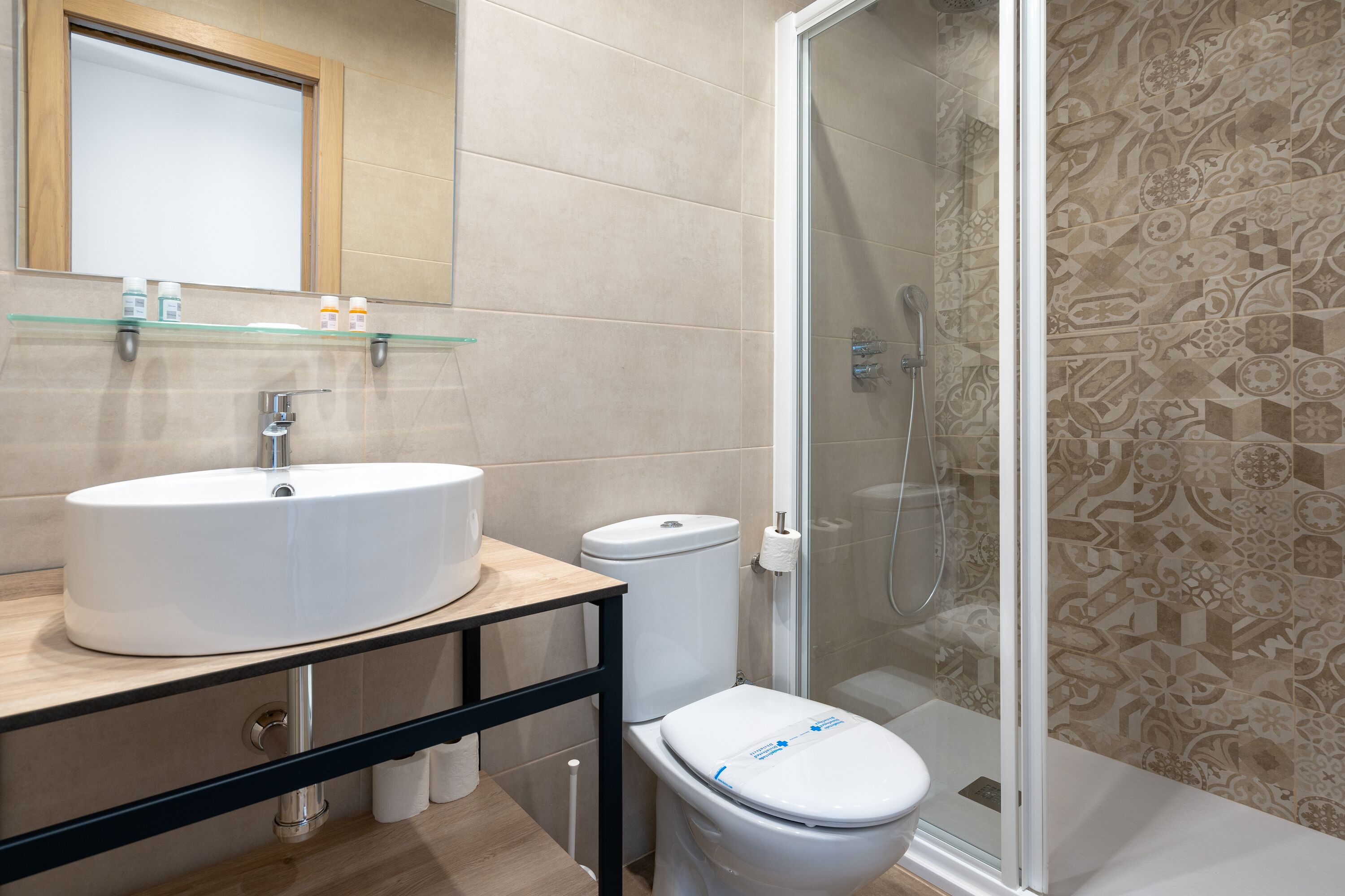 A modern bathroom with a large sink, toilet, and glass-enclosed shower.