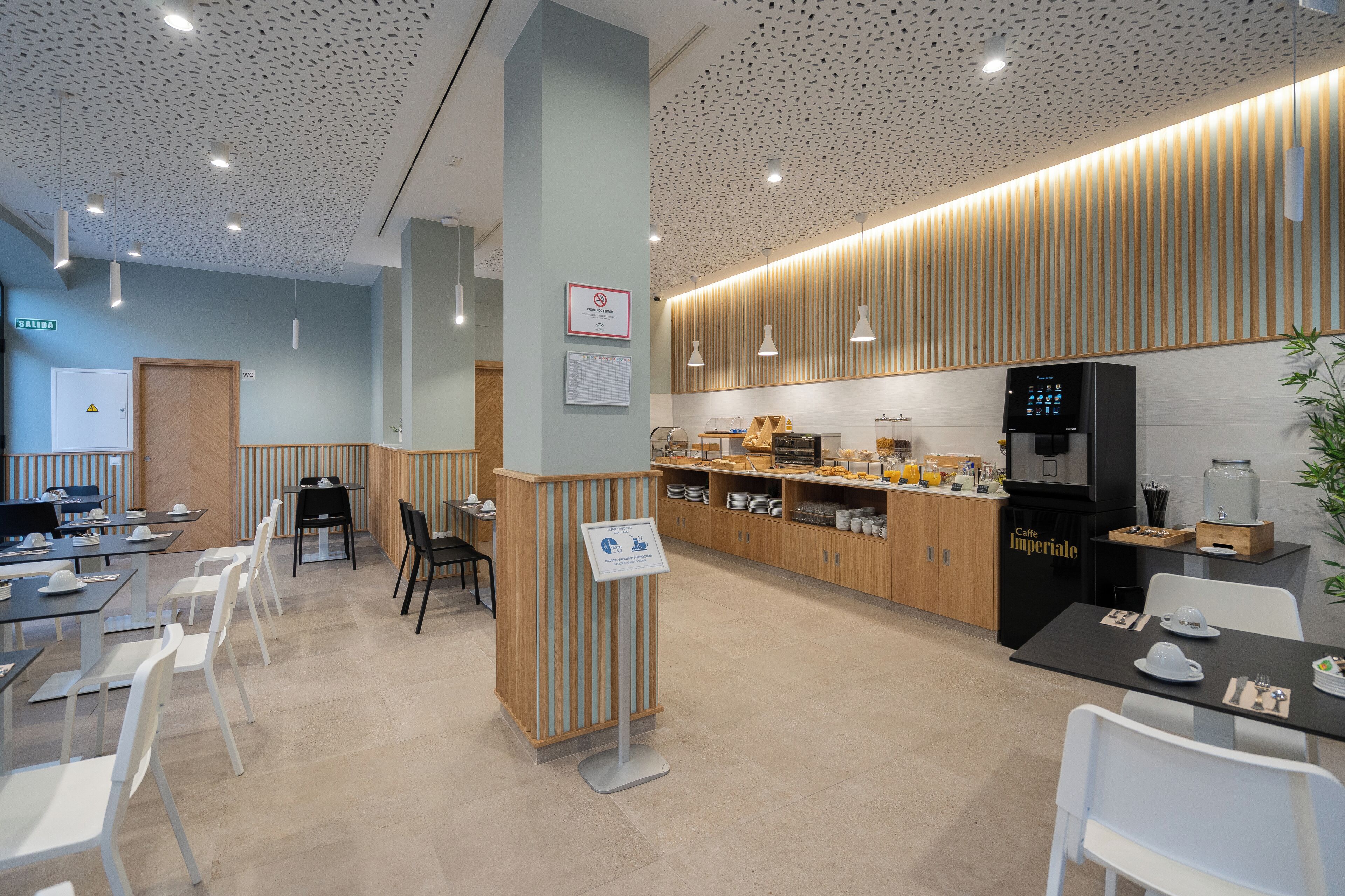 Un café moderne avec des éléments décoratifs en bois, une machine à café et un distributeur d’eau.