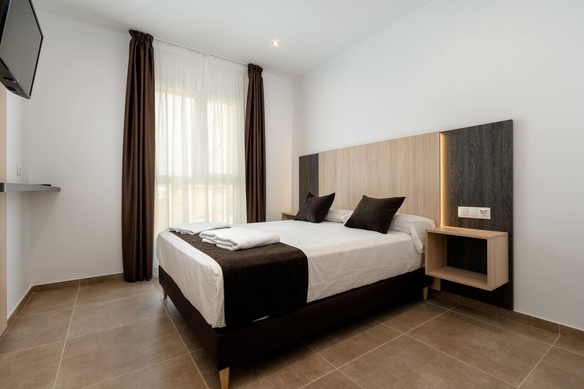 Une chambre à coucher moderne avec un grand lit, une table de chevet et une étagère intégrée.