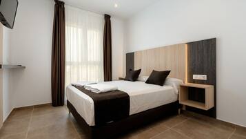 A modern bedroom with a large bed, a bedside table, and a built-in shelf.