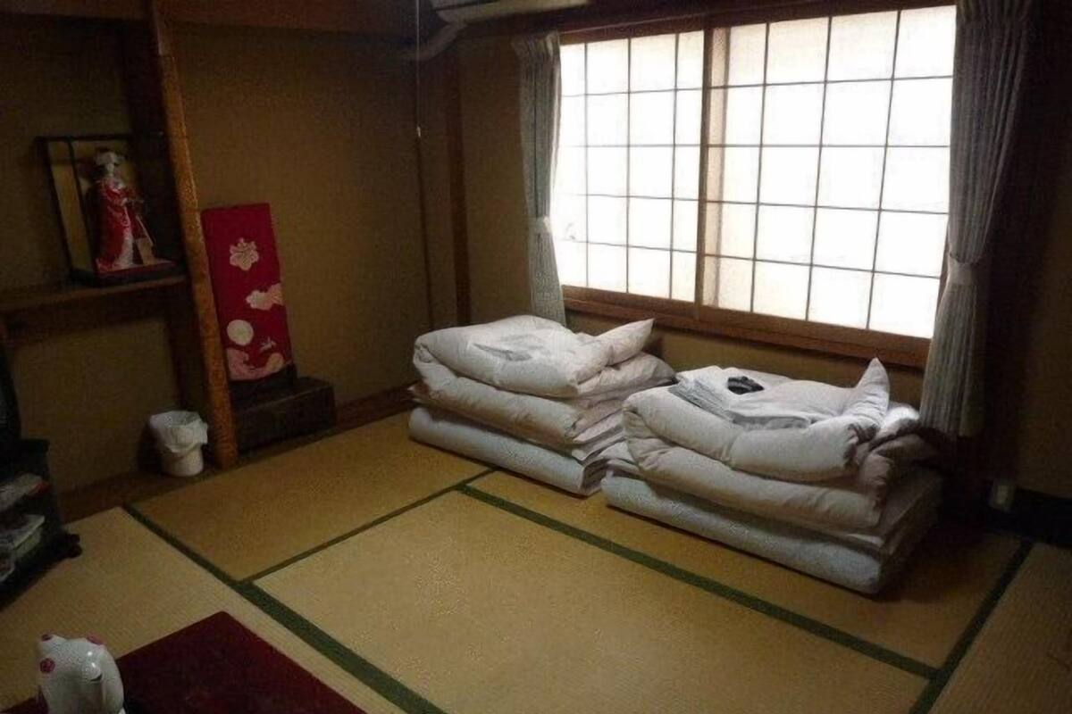 A traditional Japanese room with tatami flooring, a low wooden table, and a window with a view of the outside.