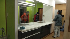 A modern kitchen with a large mirror, a sink, and a stainless steel refrigerator.