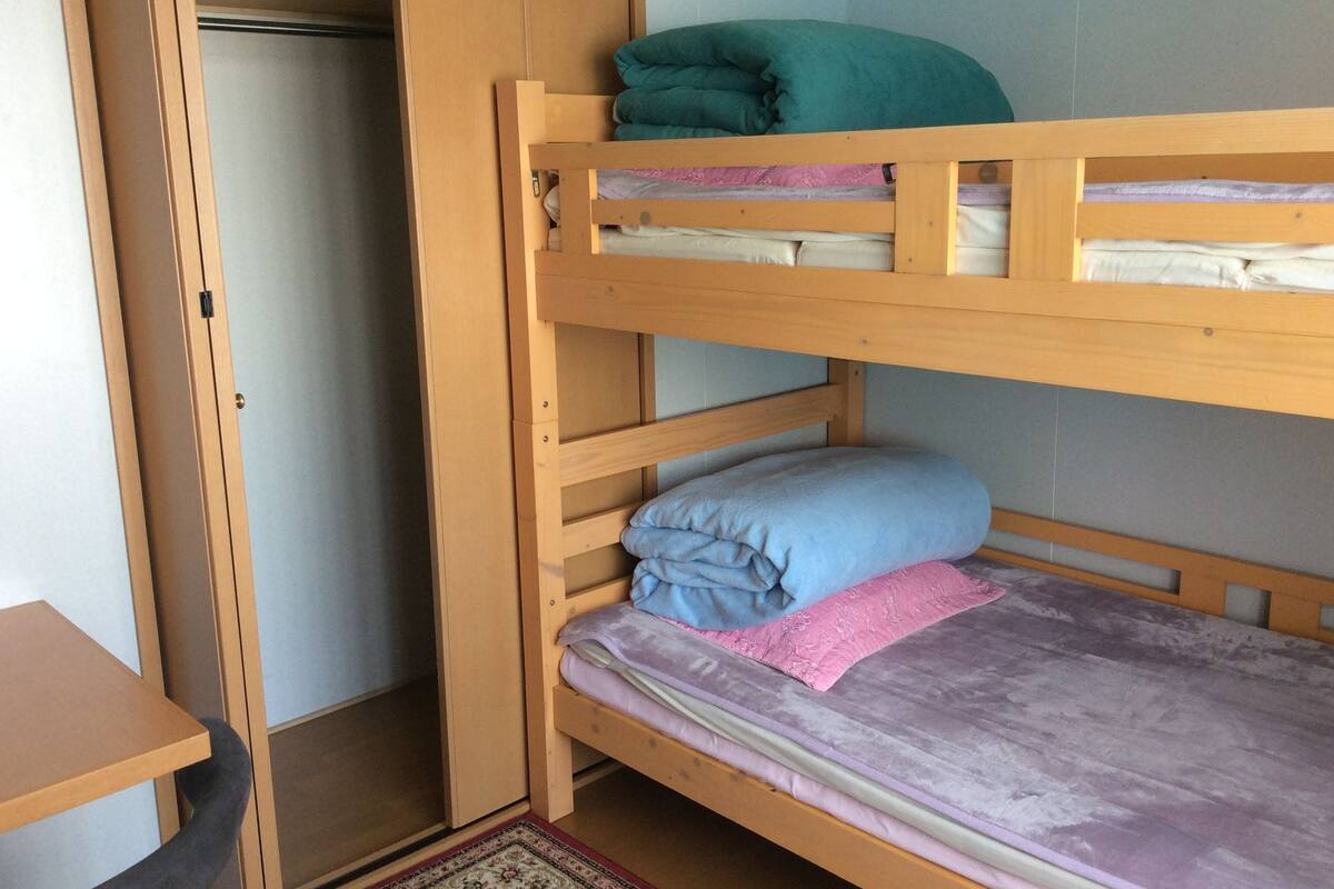 A bunk bed with a wooden frame, a desk, and a wardrobe.