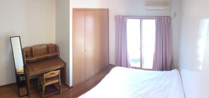 A bedroom with a bed, a desk, a wardrobe, and a window with curtains.