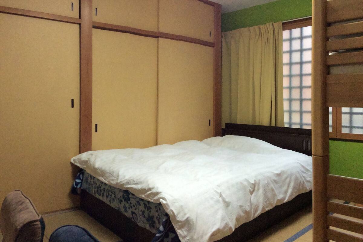 A bedroom with a bed, a wardrobe, and a window with curtains.