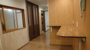 A hallway with wooden flooring and a wooden counter on the right.