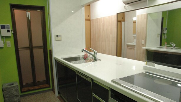 A kitchen with a stainless steel sink, a built-in stove, and a trash can.