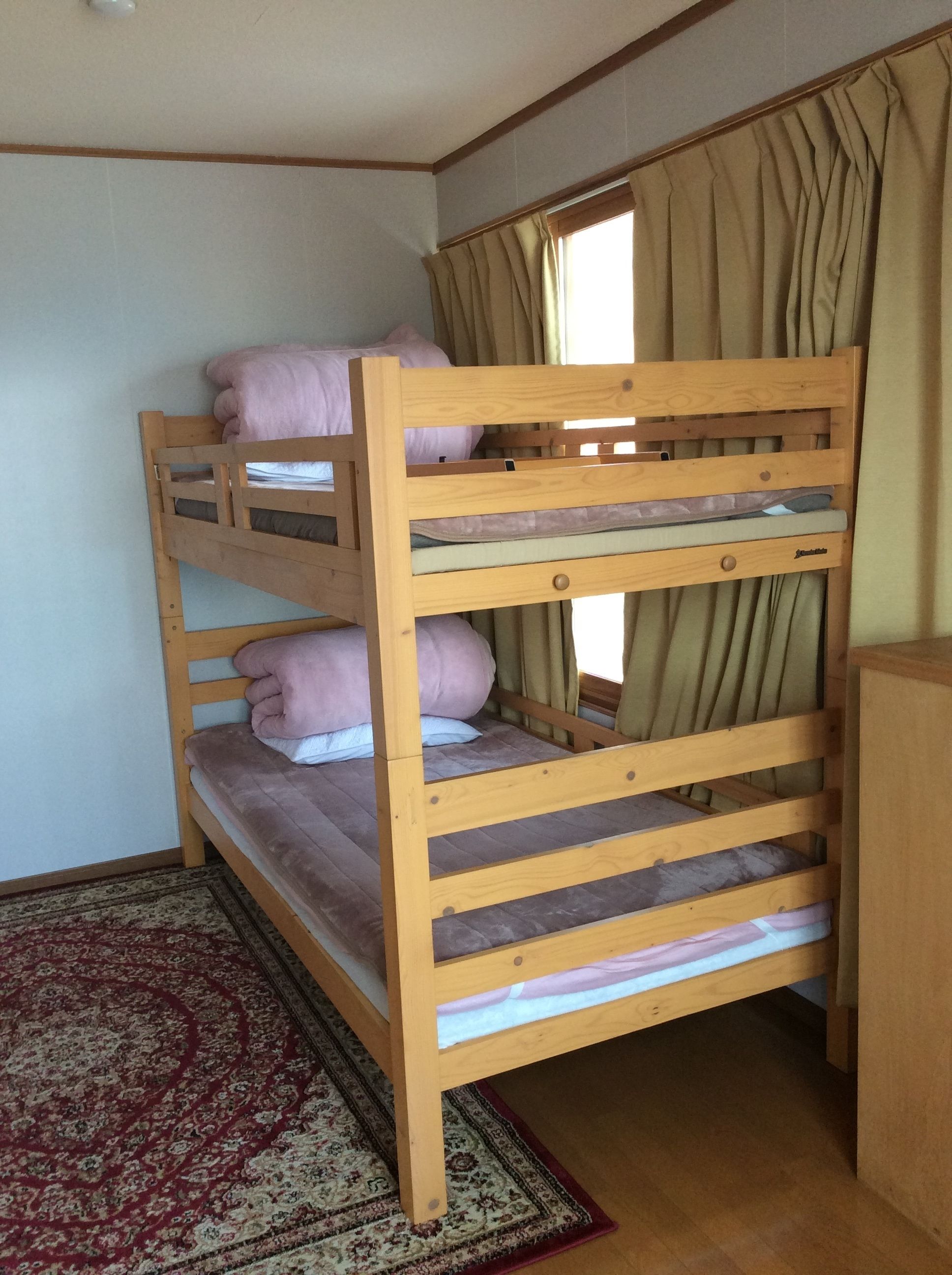 Ein Etagenbett mit zwei Schlafstellen, einem Holzkopfstück und einem kleinen Nachttisch.