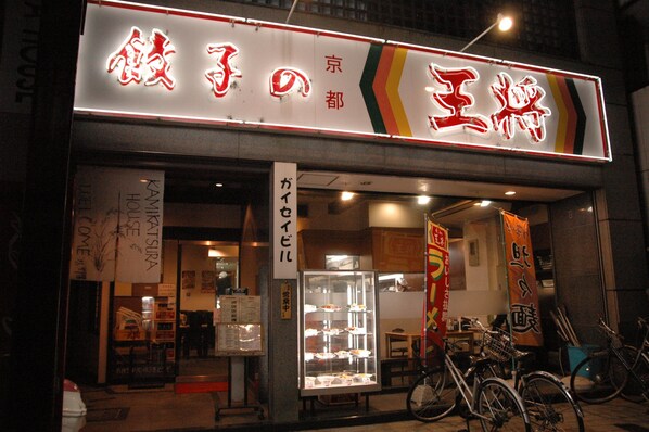 A restaurant with a neon sign, bicycle parking, and a glass display case. - Kamikatsura House (Kyoto)