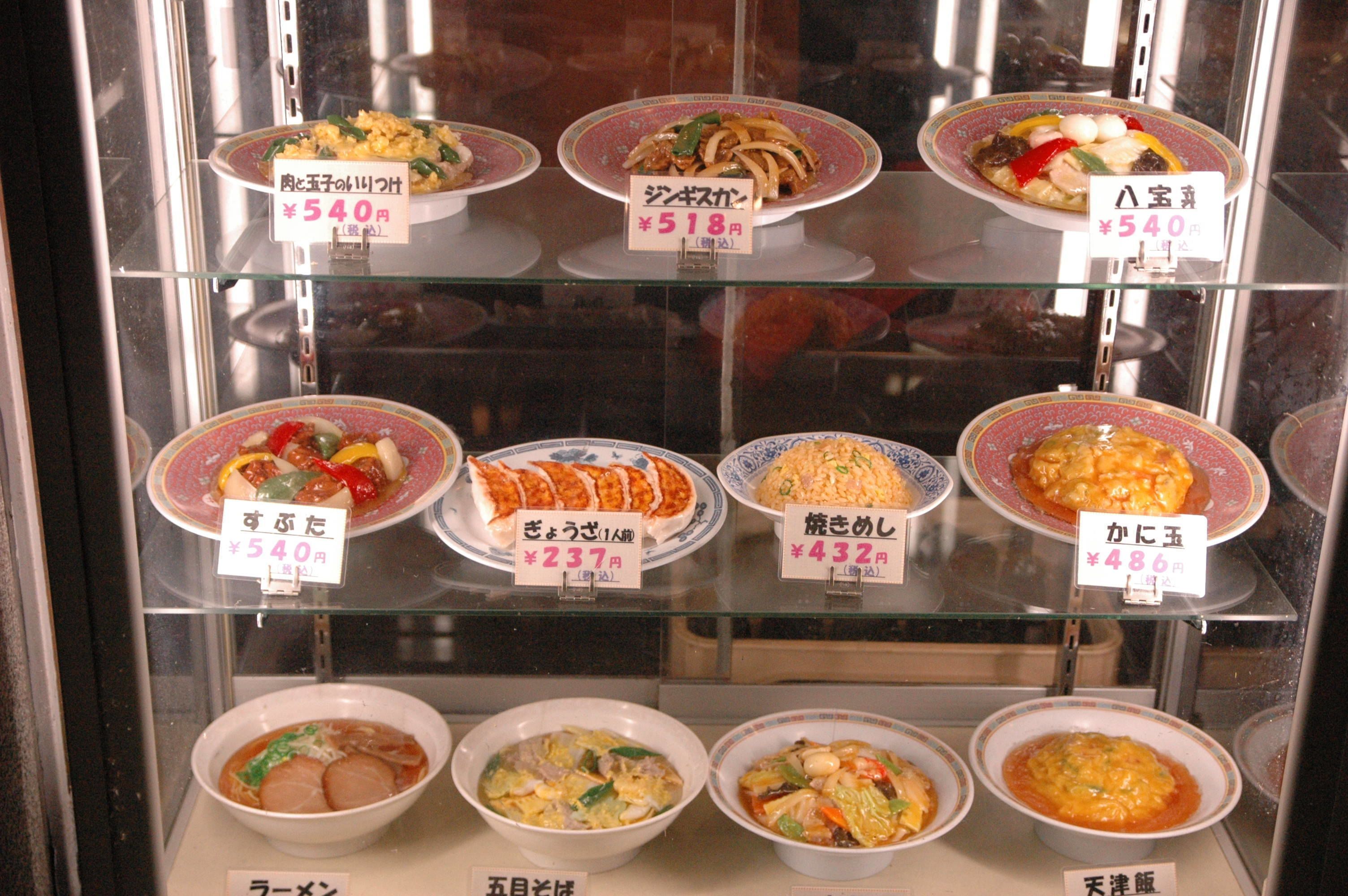 A variety of dishes displayed in a glass case with price tags.