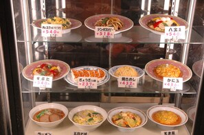 A variety of dishes displayed in a glass case with price tags.