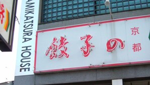 A building with a sign that reads "KAMIKASURA HOUSE" and another sign with Japanese characters.