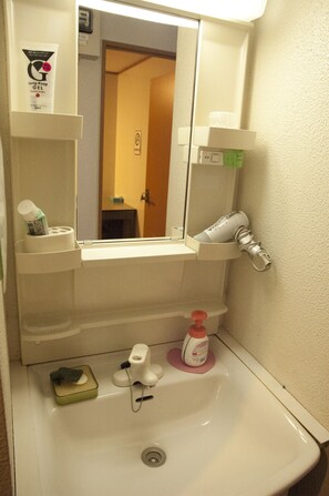 A bathroom with a white sink, a mirror, and shelves holding toiletries.