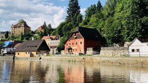 A riverside town with historic buildings, a stone wall, and a wooden bridge. - Penzion Kapr (Cesky Krumlov)